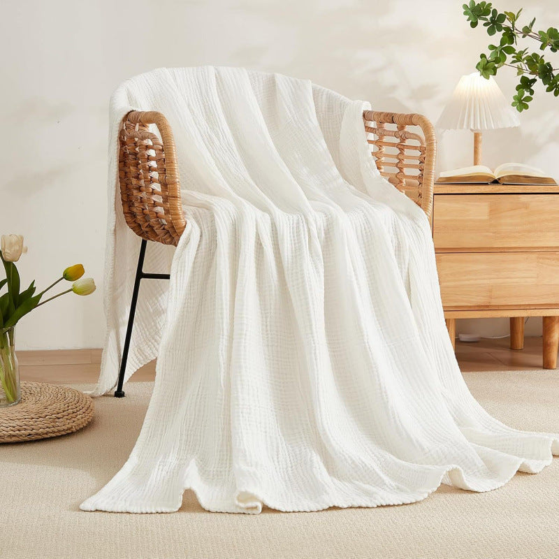 Cotton muslin blanket folded on a bed in a cozy bedroom setting